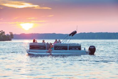 people having fun on a SunTracker Party Barge learning to drive a pontoon boat.