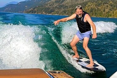 guy wake surfing behind brown boat