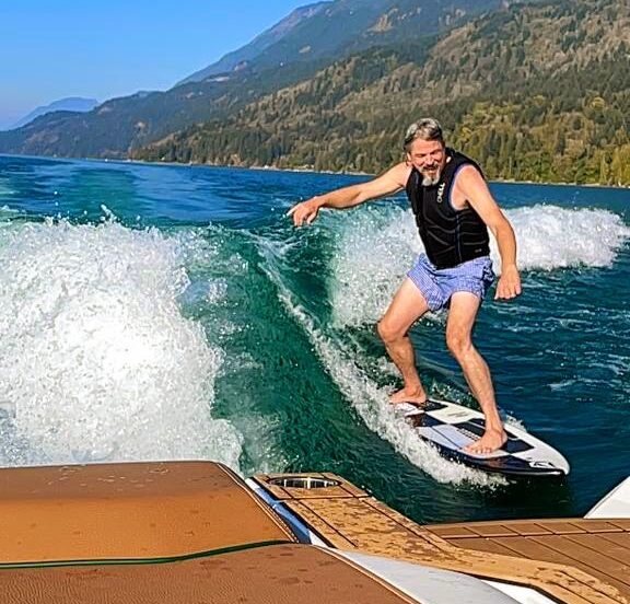guy wake surfing behind brown boat